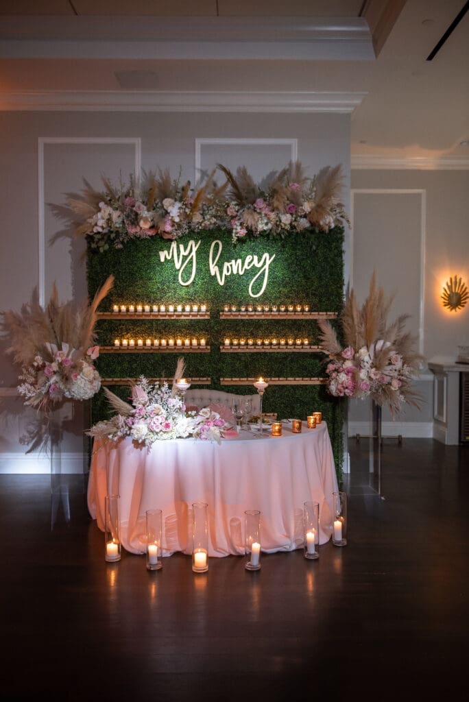 Sweetheart table at Pelican Club with romantic floral arrangements and champagne display behind the couple during their wedding reception