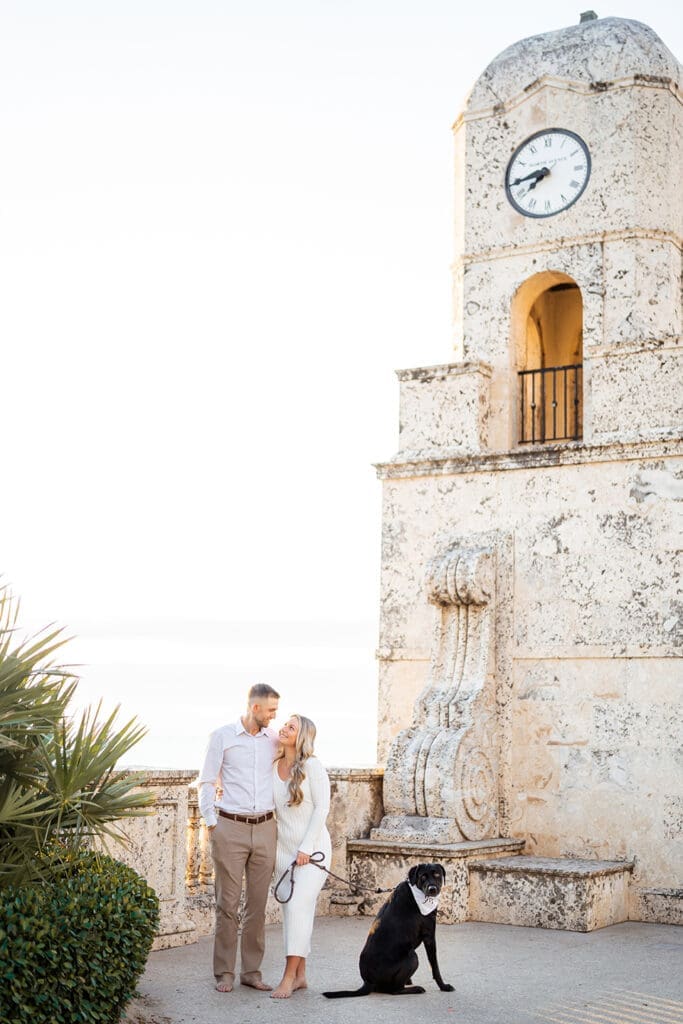 Engaged couple with their dog in front of the Worth Avenue Clock Tower in Palm Beach during engagement shoot