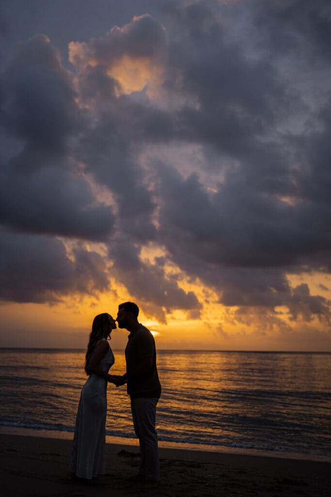 Sunrise silhouette image of couple on beach 