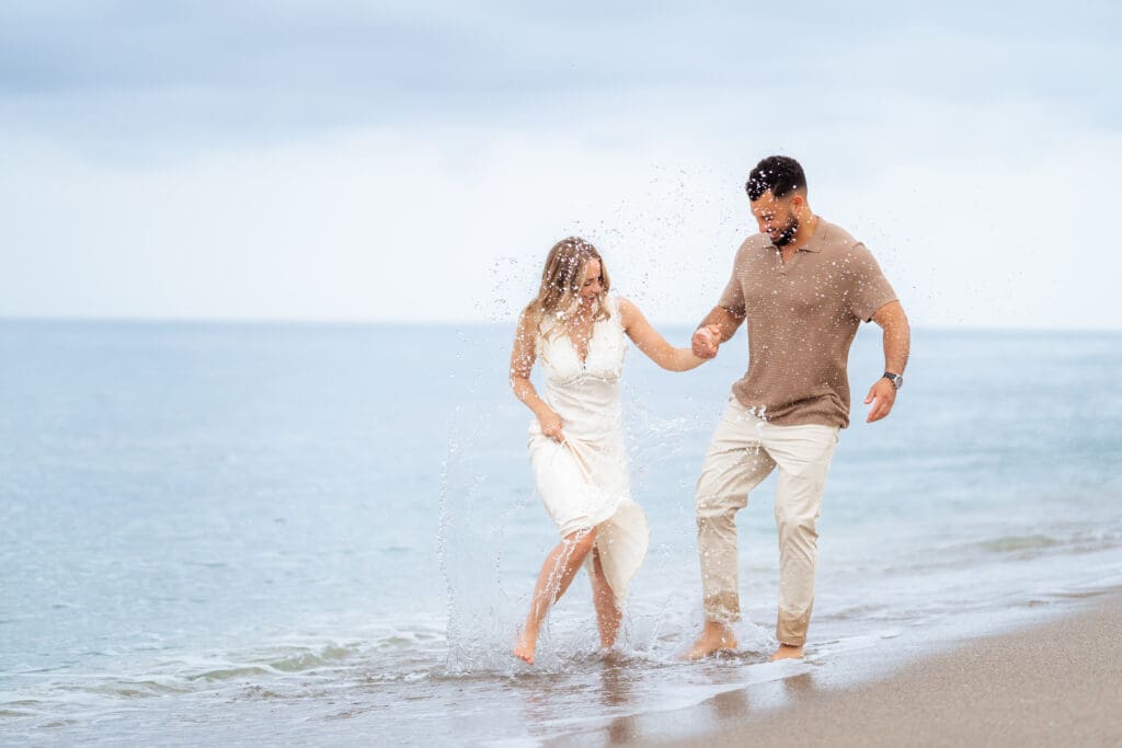 Couple playing in the water for their beach sunrise shoot