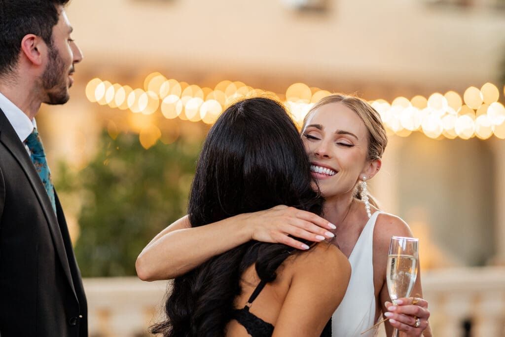 bride hugging guest at cocktail hour