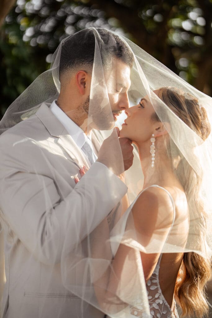 Bride and groom under veil photo.
